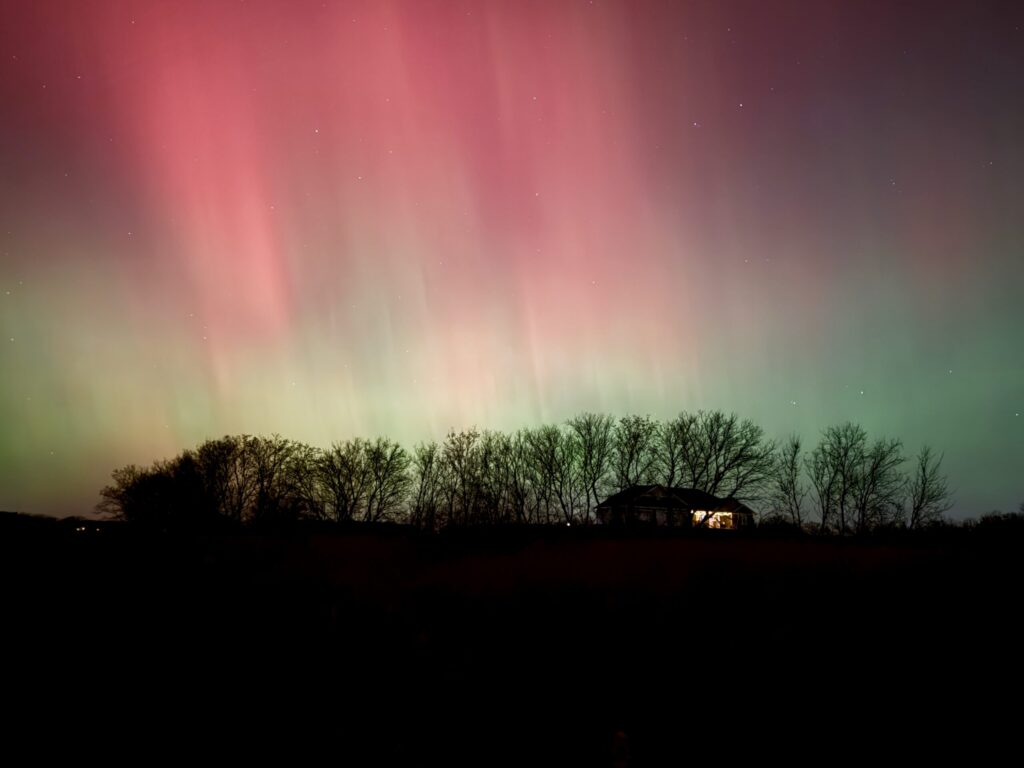 Northern lights over a field in the middle of the night.